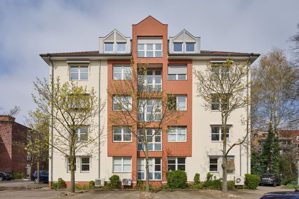 Bild einer Gewerbeimmobilie in moderner Klinkerbauweise mit zentralem Eingang, hellen Fassaden und frisch austreibenden Bäumen in urbaner Wohnlage in Hannover, Leisewitzstraße 37B.